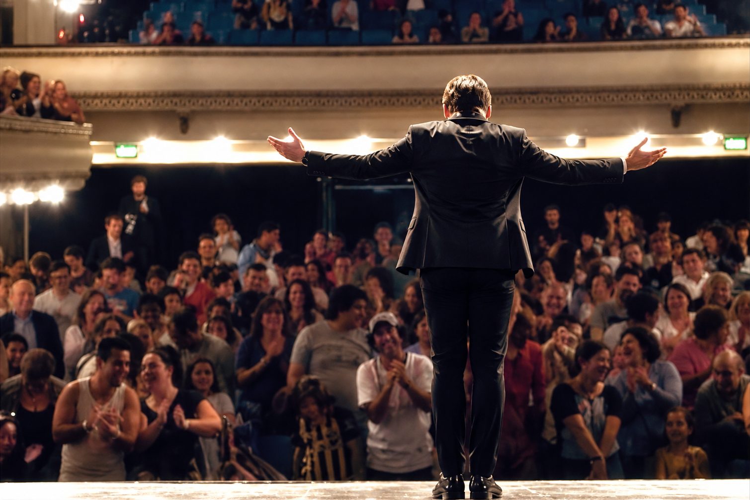 Javier Franco en el escenario de un teatro lleno, con los brazos abiertos frente al público que aplaude
